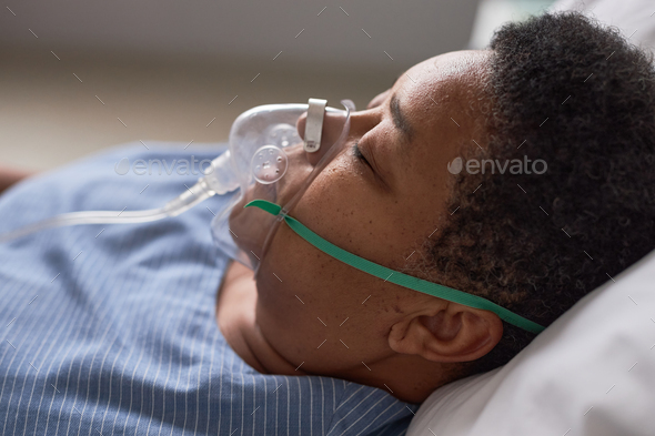 Close up side view of black senior woman with oxygen support mask in hospital