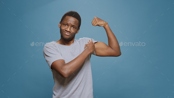 Athletic person flexing biceps muscles on camera in studio Stock Photo by  DC_Studio