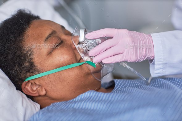 Close up of nurse placing oxygen support mask on senior patient