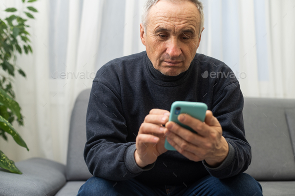 Closeup portrait headshot elderly man with glasses having trouble seeing cell phone has vision