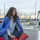 Beautiful woman in pink dress and blue jacket posing on a sailboat in a city harbor on a cloudy day. - PhotoDune Item for Sale