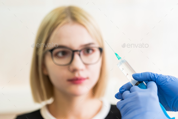 Girl shows she is afraid of injection - Stock Photo - Images