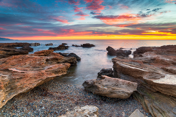 Stunning sunrise over the beach and rocks at Torre de la Sal - Stock Photo - Images