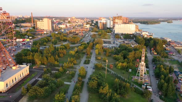 Drone View Colorful Ferris Wheel in Amusement Park on River and City Landscape alt