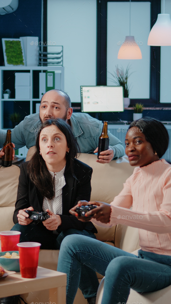 Colleagues playing video games on console with controller Stock Photo by DC_Studio