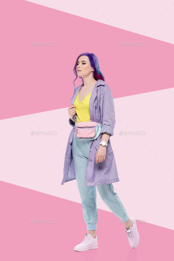 stylish young woman in purple trench coat with waist pack on creative background