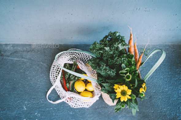 Sustainable zero waste shopping concept. Mesh bag with lemons and greens with yellow flowers.