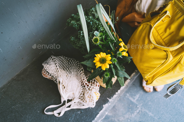 Sustainable zero waste shopping concept. Mesh bag with lemons and basket with yellow flowers.