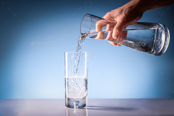 Pouring drinking water from a pitcher into a glass. Clean drinkable water concept