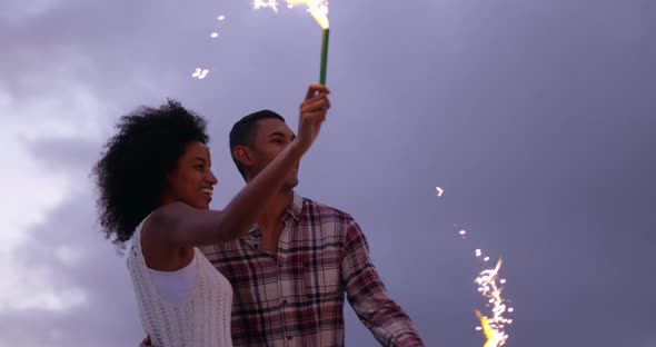 Couple playing with sparklers on beach at dusk 4k