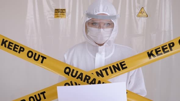 Doctor in a Medical Protective Suit Holds a Placard with the Words QUARANTINE alt
