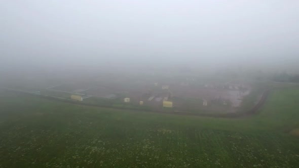 Aerial View on Oil Pumps at Oilfield Cluster in a Foggy Field After Rain