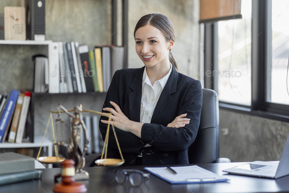 Statue of Justice and female lawyer in suit at workplace with laptop ...