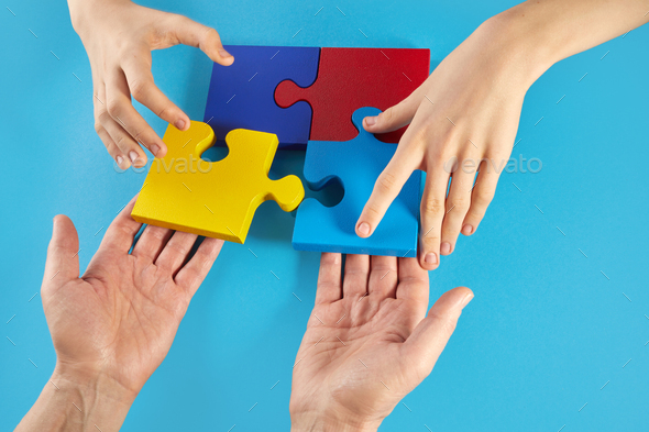 Father and autistic son hands holding jigsaw puzzle shape. World Autism Awareness Day
