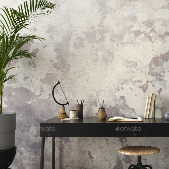 Concrete interior of home office with copy space, black desk, office accessories and plants.