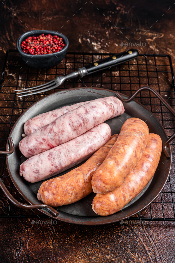 Uncooked Raw mix sausages for BBQ with spices in steel tray. Dark
