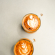Two glass cups of cappuccino with latte art on white table background. - PhotoDune Item for Sale