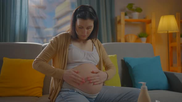 Pregnant Young Woman Uses Ointment or Body Lotion alt
