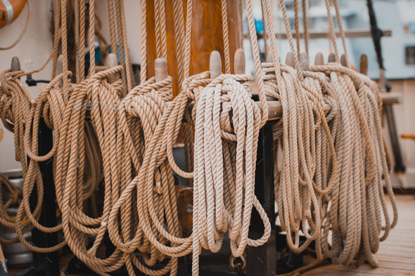 Closeup of thick ropes on a wooden stand of a ship captured during the  daytime Stock Photo by wirestock