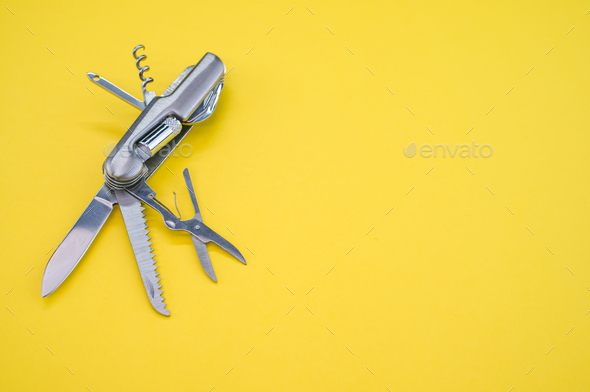High angle shot of a swiss army knife on a yellow surface