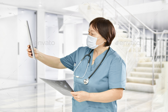 Asian woman doctor checking x-ray sheets carefully