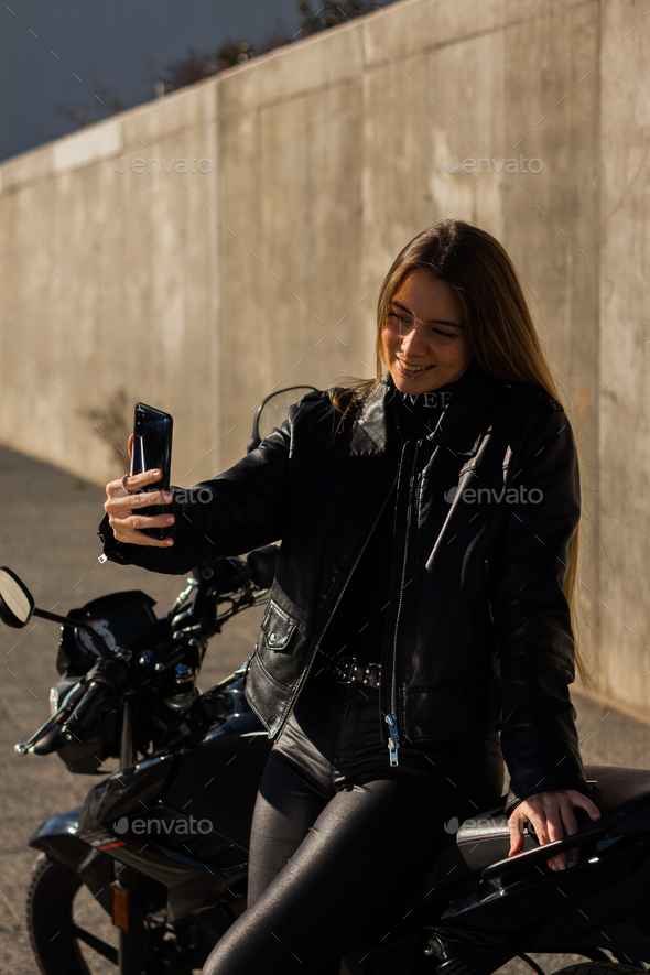 Pretty Caucasian lady taking a selfie wearing a leather jacket outfit ...