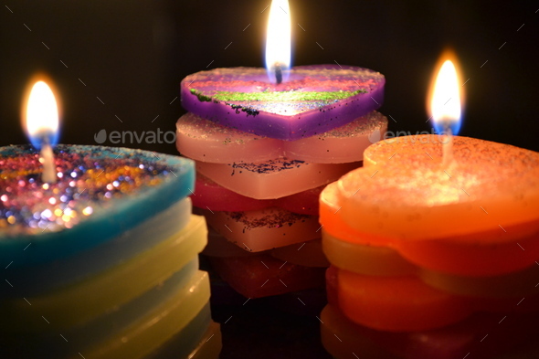 Close-up shot of three beautiful colourful heart-shaped candles with  glitter. Stock Photo by wirestock