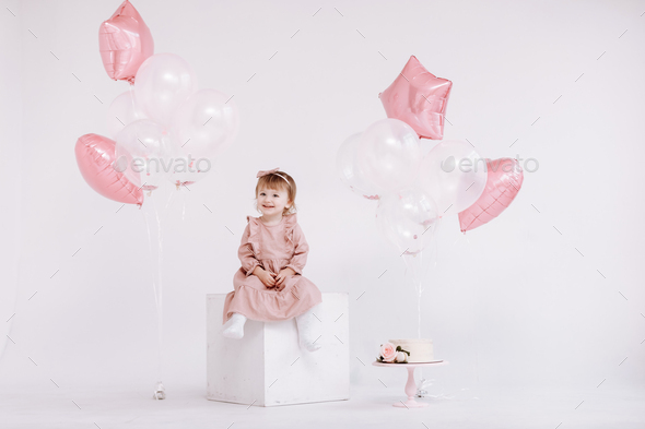 the birthday 2 years old little girl in pink dress. white cake with ...