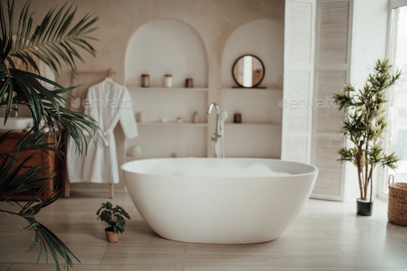 Luxury interior of big bathroom at modern african style with oval bathtub in natural lighting - Stock Photo - Images