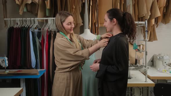 Femail seamstress taking measurements of female client using tape in atelier alt