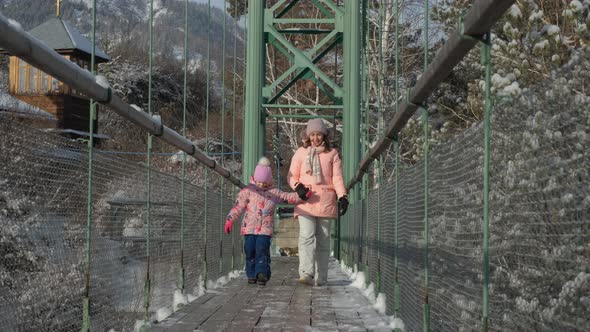 Woman with Daughter Walking on Suspension Bridge alt