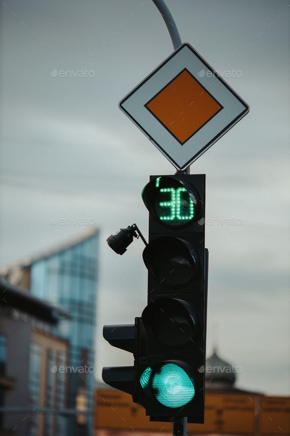 Closeup of a green traffic light for cars and the main road sign; 30 seconds left