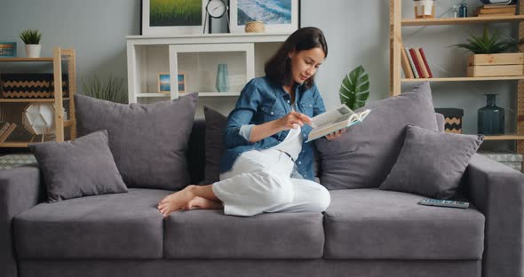 Slow Motion of Beautiful Girl Reading Book Relaxing at Home in Nice Apartment alt