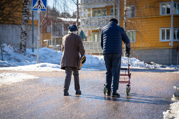 Elderly people walking with a walker down the snow-covered street