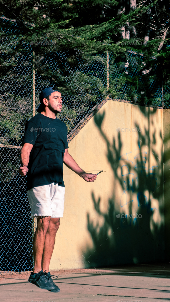 Latin male athlete exercising with a jump rope. Outdoors, forest in background.