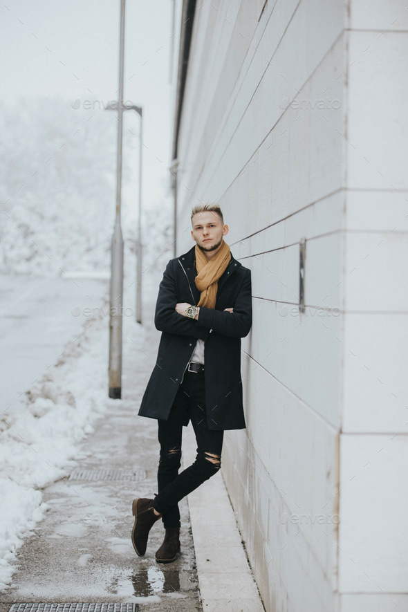 Premium Photo  Handsome young confident man in a black winter outfit with  a brown scarf strolling around the city