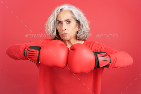 Rude mature woman in boxing gloves looking at camera