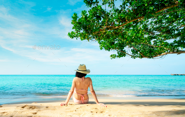 Back view of happy young Asian woman in pink swimsuit and straw hat relaxing and enjoy holiday  - Stock Photo - Images