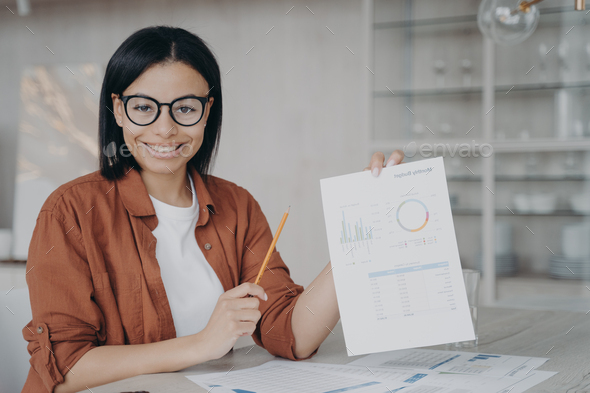 Smiling female financial analyst shows document with company statistics, presents project at desk