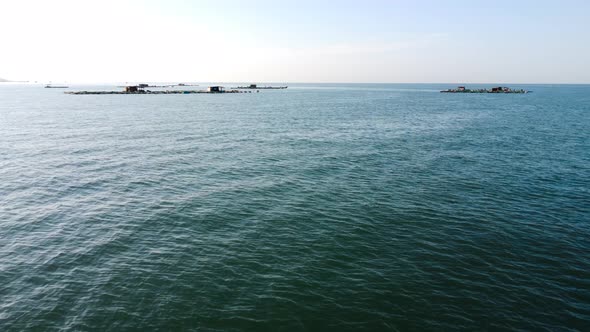 Fast aerial forward view of fish farming platforms in the sea. Vietnam. alt