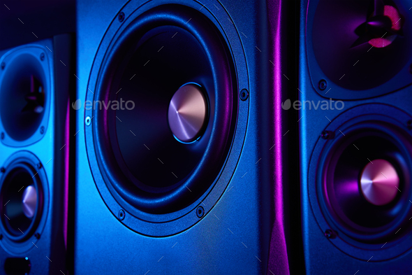 Two sound speakers and subwoofer on dark background with neon lights