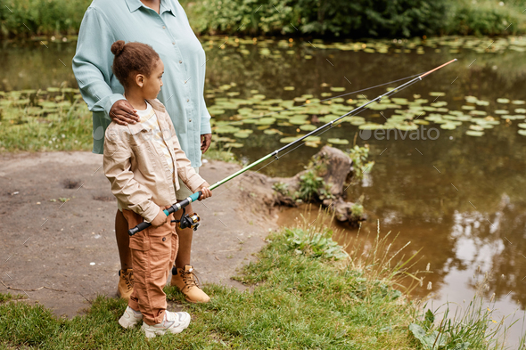 Black little girl holding fishing rod and enjoying time with