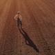 Rear view aerial of female farmer agronomist standing and looking over ploughed field - PhotoDune Item for Sale