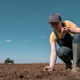 Female farmer checking the quality of ploughed field soil before sowing season - PhotoDune Item for Sale