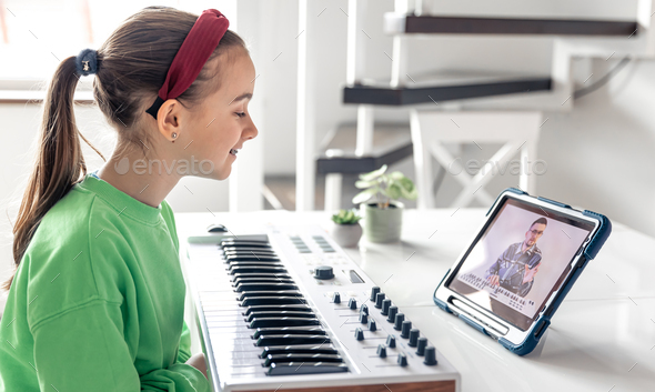 Little girl learns to play the piano with online, distance learning music.
