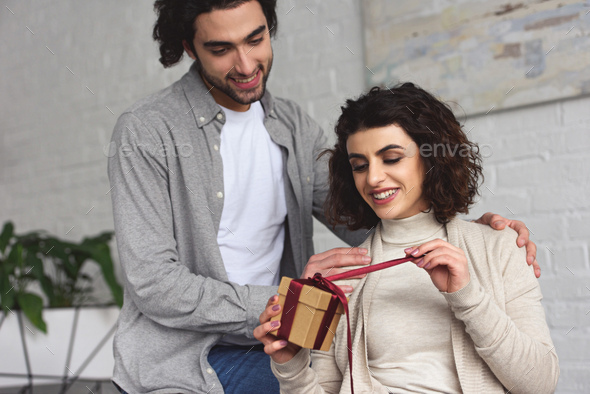 boyfriend presenting gift to girlfriend at home