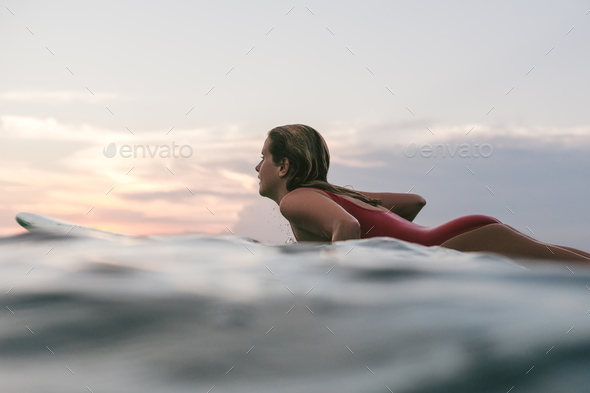 Side View Of Young Woman In Swimming Suit Surfing Alone In Ocean