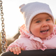 Adorable baby girl with big beautiful eyes and a beanie having fun on a swing - PhotoDune Item for Sale