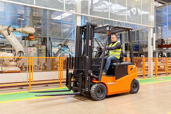 Storehouse employee in uniform working on forklift in modern automatic warehouse. Boxes are on the