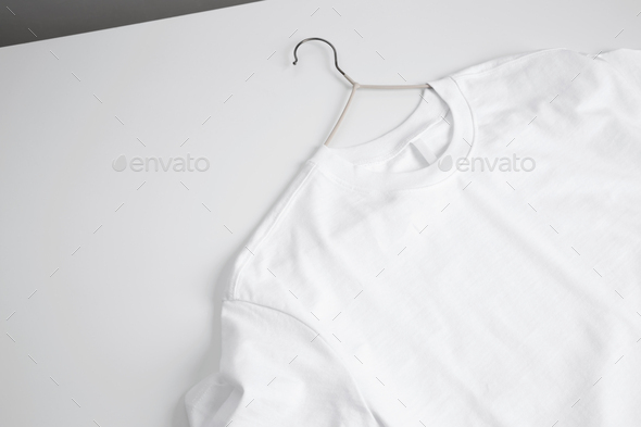 Basic white t-shirt and hanger on table. Mock up for branding t-shirt. Copy space